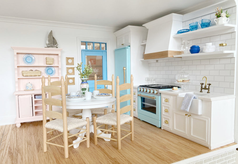 A 1:12 scale dining nook with a round white table and ladderback chairs